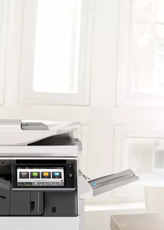 Man using laptop and smartphone with printer in foreground