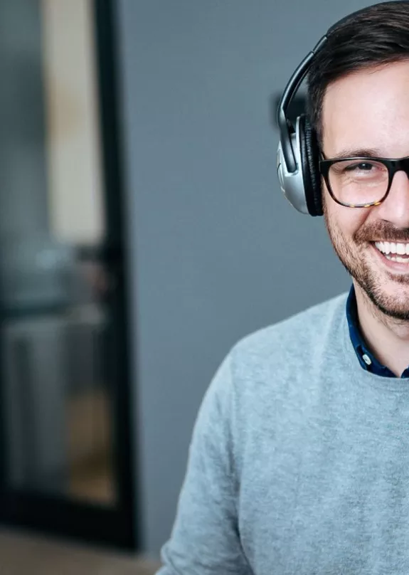 A man wearing a headset whilst using a computer